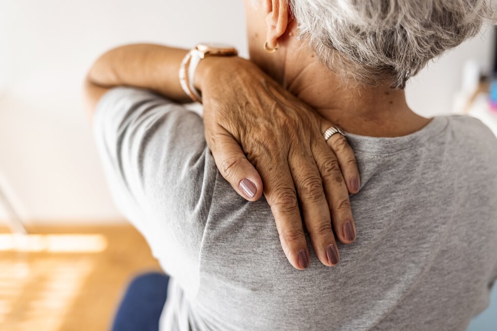 Woman with upper back and neck pain from hunched posture and rounded shoulders